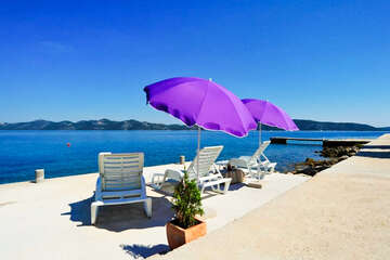 Prázdninový dům Riva - betonové molo s lehátky a slunečníky před domem, Mali Iž, ostrov Iž, Chorvatsko