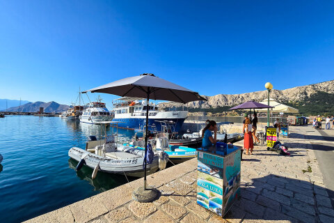 Baška - promenáda s kiosky nabízejícími lodní výlety a lodní taxi, ostrov Krk, Chorvatsko